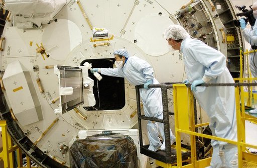 KENNEDY SPACE CENTER, FLA. -  Japanese astronaut Koichi Wakata (left) works with a tray extended from inside the Pressurized Module, or PM, part of the Japanese Experiment Module (JEM).   The PM provides a shirt-sleeve environment in which astronauts on the International Space Station can conduct mi