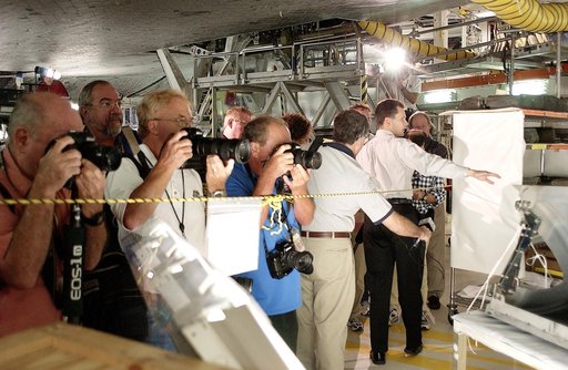 KENNEDY SPACE CENTER, FLA. -  In the Orbiter Processing Facility,  while a few photographers (left) set up for photos, NASA Vehicle Manager Scott Thurston (right, with arm extended) talks about the Reinforced Carbon-Carbon panel at right.   The media was invited to see the orbiter Atlantis as it is 