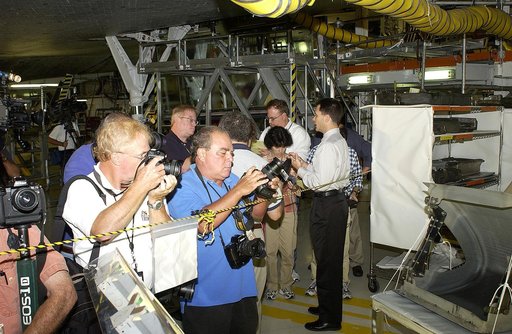 KENNEDY SPACE CENTER, FLA. -  In the Orbiter Processing Facility, while a few photographers (left) set up for photos of a Reinforced Carbon-Carbon panel at far right, NASA Vehicle Manager Scott Thurston (right) talks to other media.   The media was invited to see the orbiter Atlantis as it is being 