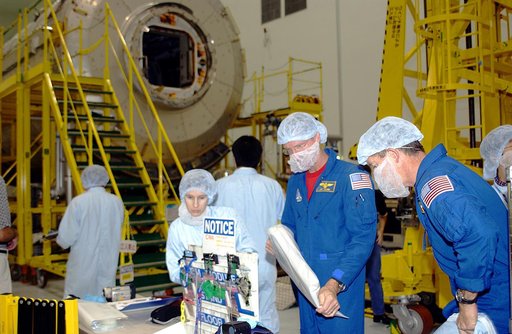 KENNEDY SPACE CENTER, FLA. - In the Space Station Processing Facility, STS-115 Mission Specialist Joseph Tanner (left) and STS-117 Mission Specialist James Reilly (right) are donning protective clothing to interface with the Japanese Experiment Module (JEM), in the background.  Equipment familiariza