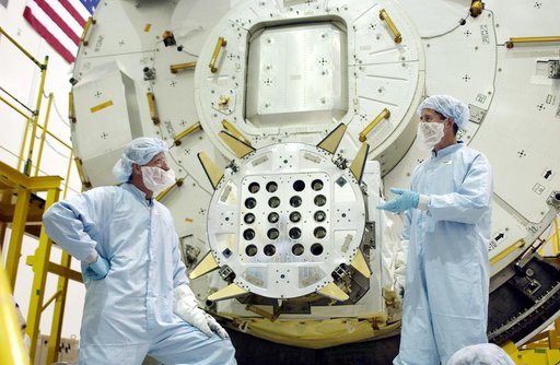 KENNEDY SPACE CENTER, FLA. - In the Space Station Processing Facility, STS-115 Mission Specialist Joseph Tanner (left) and STS-117 Mission Specialist James Reilly (right) talk after removing a cover from the Exposed Facility Berthing Mechanism (EFBM) on the Japanese Experiment Module (JEM) behind th