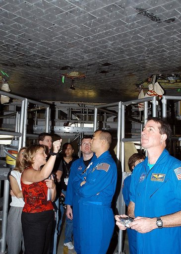 KENNEDY SPACE CENTER, FLA. -  In the Orbiter Processing Facility, STS-114 crew members look at the tiles underneath Atlantis.  From center, left to right (in uniform), are Pilot James Kelly, Mission Specialist Soichi Noguchi, Mission Specialists Wendy Lawrence and Stephen Robinson.  Accompanying the