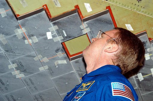 KENNEDY SPACE CENTER, FLA. -  In the Orbiter Processing Facility, STS-114 Mission Specialist Andy Thomas takes a close look at the some of the tiles underneath Atlantis.  Thomas is a new addition to the mission crew.  The STS-114 crew is at KSC to take part in crew equipment and orbiter familiarizat