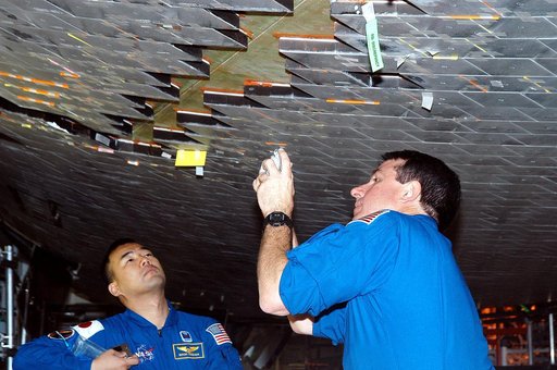 KENNEDY SPACE CENTER, FLA. -  In the Orbiter Processing Facility, STS-114 Mission Specialists Soichi Noguchi and Stephen Robinson take a close look at the some of the tiles underneath Atlantis.  Noguchi is with the Japan Aerospace Exploration Agency, JAXA.  The STS-114 crew is at KSC to take part in
