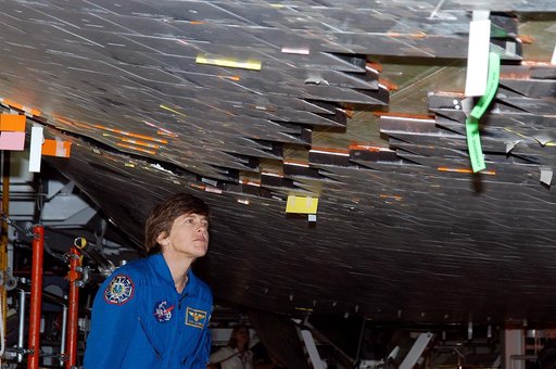 KENNEDY SPACE CENTER, FLA. -  In the Orbiter Processing Facility, STS-114 Mission Specialist Wendy Lawrence takes a close look at the some of the tiles underneath Atlantis.  Lawrence is a new addition to the mission crew.  The STS-114 crew is at KSC to take part in crew equipment and orbiter familia