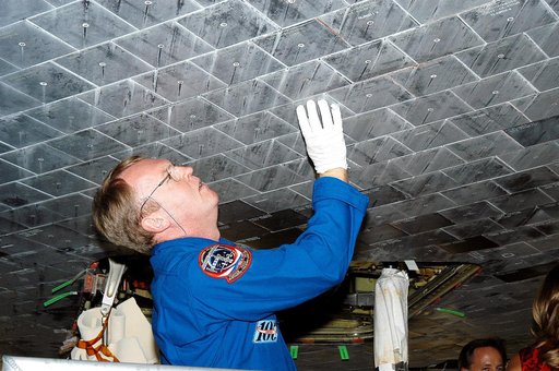 KENNEDY SPACE CENTER, FLA. -  In the Orbiter Processing Facility, STS-114 Mission Specialist Andy Thomas takes a close look at the some of the tiles underneath Atlantis.  Thomas is a new addition to the mission crew.  The STS-114 crew is at KSC to take part in crew equipment and orbiter familiarizat