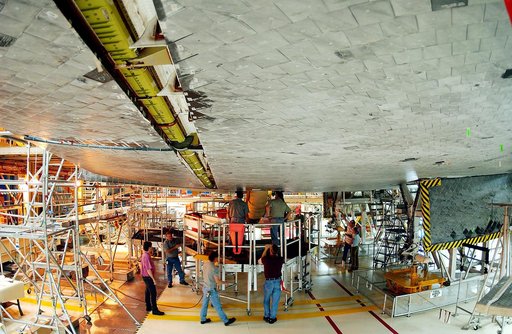 KENNEDY SPACE CENTER, FLA. -  Workers in the Orbiter Processing Facility oversee installation of the liquid oxygen feedline for the 17-inch disconnect on the orbiter Discovery.  The 17-inch liquid oxygen and liquid hydrogen disconnects provide the propellant feed interface from the external tank to 