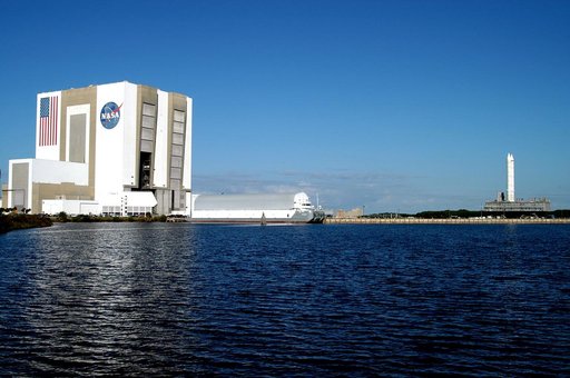 KENNEDY SPACE CENTER, FLA. - Viewed across the turn basin in the Launch Complex 39 Area, the crawler transporter slowly moves the Mobile Launcher Platform (MLP), carrying a set of twin solid rocket boosters, away from the Vehicle Assembly Building (VAB).  The journey is in support of engineering ana