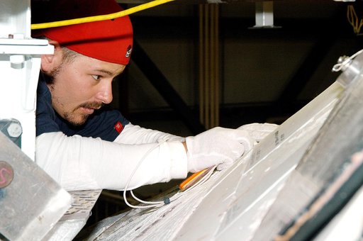 KENNEDY SPACE CENTER, FLA. - In the Orbiter Processing Facility, United Space Alliance technician Chris Moore performs gap tests on the tiles of the nose of orbiter Atlantis as part of return-to-flight activities.  Atlantis is scheduled for mission STS-114, a return-to-flight test mission to the Int