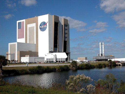 KENNEDY SPACE CENTER, FLA. - Seen across the water of the Launch Complex 39 turn basin, a crawler-transporter, carrying Mobile Launcher Platform (MLP) number 3 with a set of twin solid rocket boosters bolted atop, crawls out of the 525-foot-tall Vehicle Assembly Building during the second engineerin