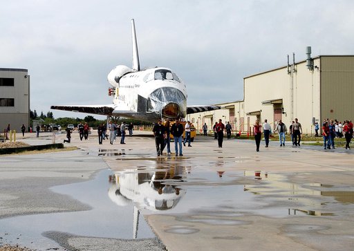 KENNEDY SPACE CENTER, FLA. - The Space Shuttle orbiter Atlantis is reflected in a rain puddle as it is towed from the Orbiter Processing Facility (OPF) to the Vehicle Assembly Building (VAB). The move will allow work to be performed in the OPF that can only be accomplished while the bay is empty. Wo