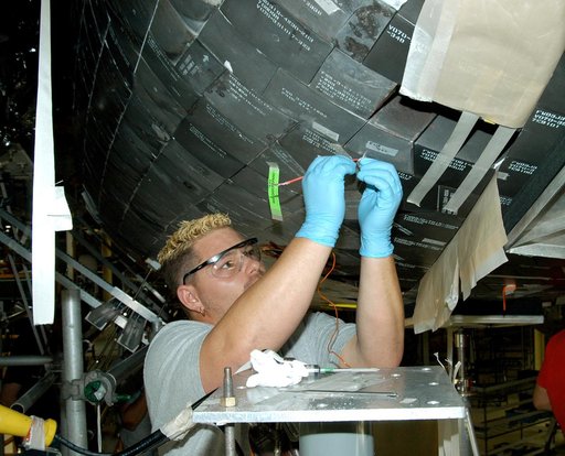 KENNEDY SPACE CENTER, FLA. -  In the Orbiter Processing Facility, KSC employee Chris Moore repairs tile on the forward area of the orbiter Discovery. The vehicle has undergone Orbiter Major Modifications in the past year, which includes tile check and repair. The tiles are part of the Orbiter Therma