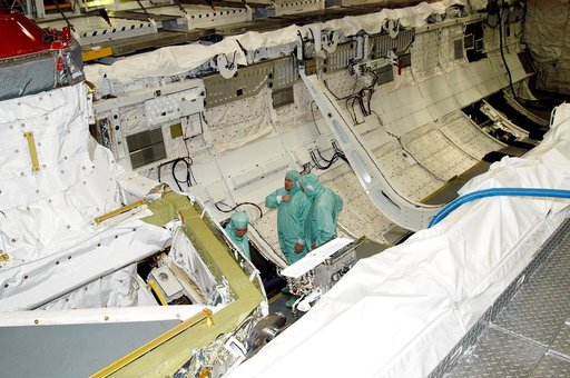KENNEDY SPACE CENTER, FLA. -- In Orbiter Processing Facility Bay 1, NASA Deputy Associate Administrator for Space Station and Shuttle Programs Michael Kostelnik (left) and United Space Alliance (USA) Vice President and Space Shuttle Program Manager Howard DeCastro (right) are briefed by a USA techni