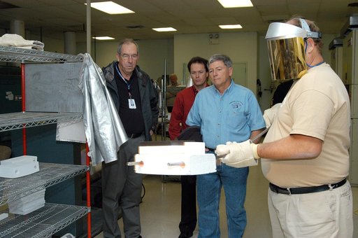 KENNEDY SPACE CENTER, FLA. -- United Space Alliance (USA) Vice President and Space Shuttle Program Manager Howard DeCastro (left) and NASA Deputy Associate Administrator for Space Station and Shuttle Programs Michael Kostelnik (third from left) watch as a USA technician (right) creates a tile for us