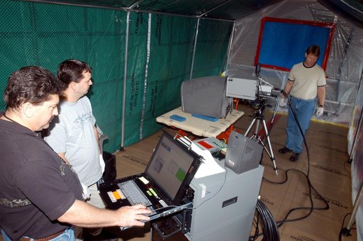 KENNEDY SPACE CENTER, FLA. -  Dan Phillips (left) and Donald Nielen, with United Space Alliance, watch a monitor as  Jim Landy, NDE specialist with USA, prepares to examine a Reinforced Carbon Carbon panel (on the table, center) using flash thermography.  A relatively new procedure at KSC, thermogra