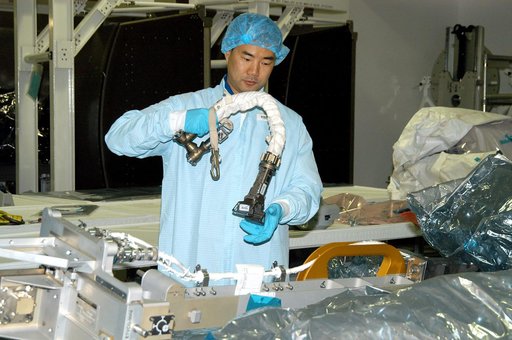 KENNEDY SPACE CENTER, FLA. -  Dressed in protective suits, STS-114 Mission Specialist Soichi Noguchi, with the Japanese Aerospace Exploration Agency (JAXA), handles equipment that will be used on the mission.  He and other crew members are at KSC for equipment familiarization.  STS-114 is classified