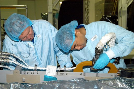 KENNEDY SPACE CENTER, FLA. -  Dressed in protective suits, STS-114 Mission Specialist Andrew Thomas (left) and Soichi Noguchi, who is with the Japanese Aerospace Exploration Agency (JAXA), handle equipment in the Space Station Processing Facility that will be used on the mission.  They and other cre