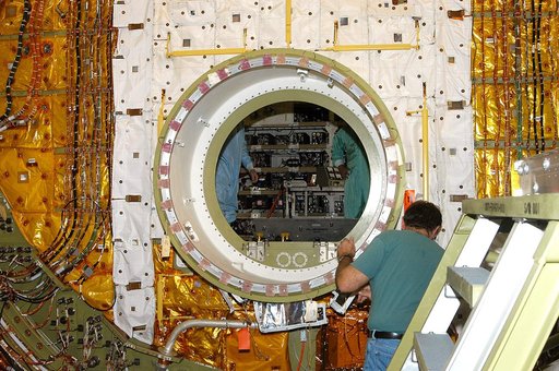 KENNEDY SPACE CENTER, FLA. -  A worker in the Orbiter Processing Facility checks the open hatch of the airlock in Discovery’s payload bay. The airlock is normally located inside the middeck of the spacecraft’s pressurized crew cabin. The airlock is sized to accommodate two fully suited flight crew m