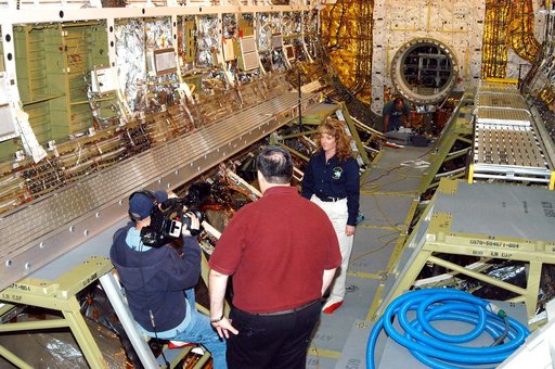 KENNEDY SPACE CENTER, FLA. -  Standing inside Discovery’s payload bay, Carol Scott (right), lead orbiter engineer, talks about her job as part of a special feature for the KSC Web.  With his back to the camera is Bill Kallus, Media manager in the KSC Web Studio.  Behind Scott can be seen the open ha