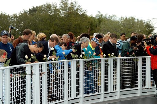 KENNEDY SPACE CENTER, FLA. -  Following the memorial service for the crew of Columbia at the Space Memorial Mirror, visitors place roses in the wire mesh fence surrounding the mirror.  Feb. 1 is the one-year anniversary of the loss of the crew and orbiter Columbia in a tragic accident as the ship re