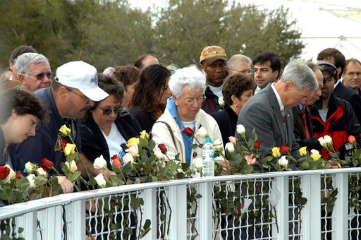 KENNEDY SPACE CENTER, FLA. -  Following the memorial service for the crew of Columbia at the Space Memorial Mirror, visitors place roses in the wire mesh fence surrounding the mirror.  Feb. 1 is the one-year anniversary of the loss of the crew and orbiter Columbia in a tragic accident as the ship re