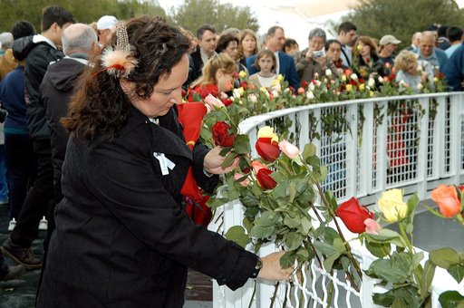 KENNEDY SPACE CENTER, FLA. - Following the memorial service for the crew of Columbia at the Space Memorial Mirror, Louise Kleba, who is with United Space Alliance, joins other visitors placing roses in the wire mesh fence surrounding the mirror.  Feb. 1 is the one-year anniversary of the loss of the