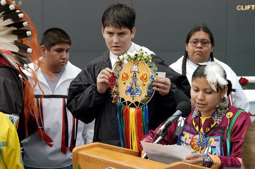 KENNEDY SPACE CENTER, FLA. - A member of the Shoshone-Bannock Native American community from Fort Hall, Idaho, reads a tribute to the crew of Columbia while another displays a handmade item with the STS-107 logo.  Dancers from Shoshone-Bannock Junior-Senior High School performed a healing ceremony d