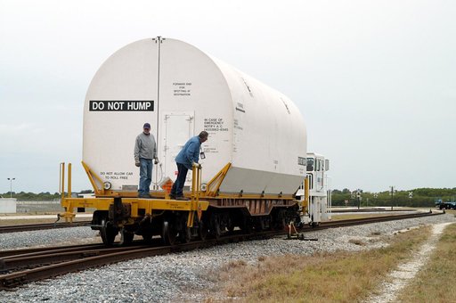 KENNEDY SPACE CENTER, FLA. - Workers ride the rails along with a container enclosing a segment of a solid rocket booster being moved to the main track.  Several segments are being returned to Utah for testing.  The segments were part of the STS-114 stack.  It is the first time actual flight segments