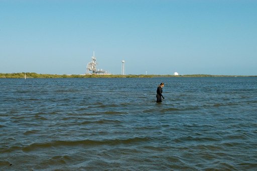 KENNEDY SPACE CENTER, FLA. - Karen Holloway-Adkins, KSC wildlife specialist, searches the Banana River for a grass specimen. In the background is one of the launch pads.  The biologist is studying the life history of sea turtles, especially what they eat, where they lay their eggs and what factors m