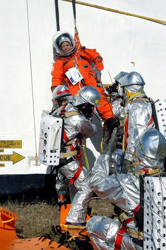 KENNEDY SPACE CENTER, FLA. - Emergency crew members on the ground take hold of a volunteer “astronaut” lowered from the top of the orbiter crew compartment mock-up that is the scene of a “Mode VII” emergency landing simulation at Kennedy Space Center.  The purpose of the Mode VII is to exercise emer