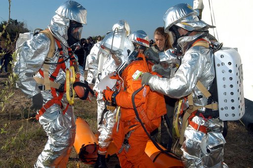 KENNEDY SPACE CENTER, FLA. - Emergency crew members help a volunteer “astronaut” onto the ground after being lowered from the top of the orbiter crew compartment mock-up that is the scene of a “Mode VII” emergency landing simulation at Kennedy Space Center.  The purpose of the Mode VII is to exercis
