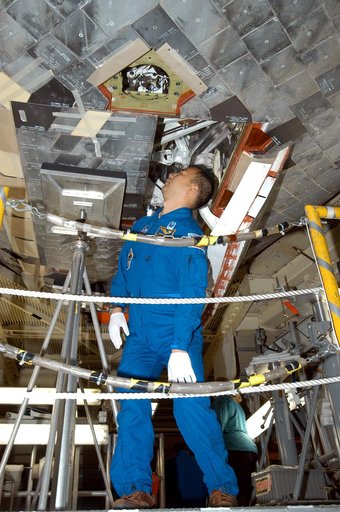 KENNEDY SPACE CENTER, FLA. - STS-114 Mission Specialist Soichi Noguchi looks at tile on the underside of the orbiter Discovery.  Noguchi is with the Japanese Aerospace and Exploration Agency.   He and other crew members are at KSC becoming familiar with Shuttle and mission equipment. The mission is 