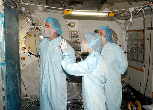 KENNEDY SPACE CENTER, FLA. - - In the Space Station Processing Facility, STS-114 Mission Specialist Stephen Robinson (left) learns about the Japanese Experiment Module (JEM) from Jennifer Goldsmith (center), with United Space Alliance at Johnson Space Center, and Louise Kleba (right), with USA at KS
