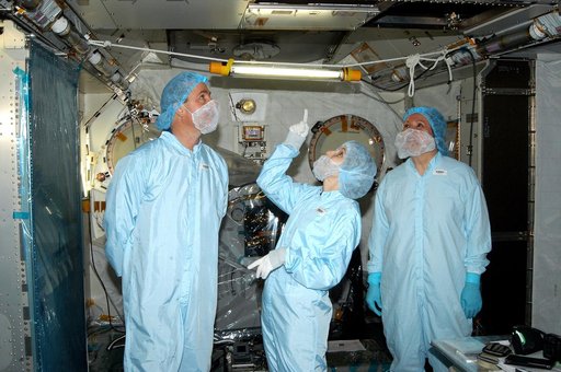 KENNEDY SPACE CENTER, FLA. - In the Space Station Processing Facility, STS-114 Mission Specialist Stephen Robinson (left) looks at an area overhead in the Japanese Experiment Module (JEM). In the center is Jennifer Goldsmith, with United Space Alliance at Johnson Space Center, and at right is Louise