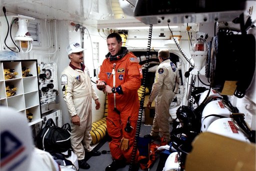 KENNEDY SPACE CENTER, FLA. -  STS-81 Mission Commander Michael Baker prepares to enter the Space Shuttle Atlantis at Launch Pad 39B with help from White Room closeout crew members Chris Meinert (left) and Danny Wyatt.