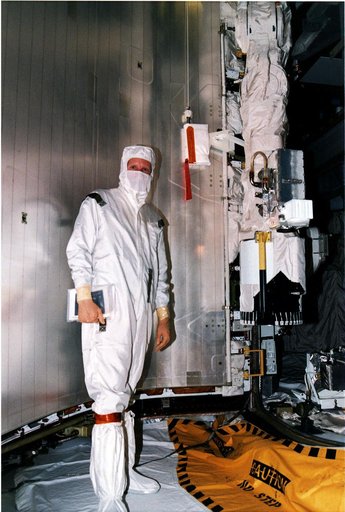 KENNEDY SPACE CENTER, FLA. -   STS-82 Mission Specialist Steven A Hawley stands beside part of Discovery's Remote Manipulator System (RMS) arm, at right, which he will operate for the capture, berthing and redeployment of the Hubble Space Telescope (HST).  The robotic arm also will be used as work p