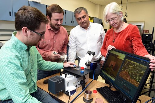 Graduate students Chris Hill and Ryan Anderson examine a cross section of the prototype rocket engine igniter.