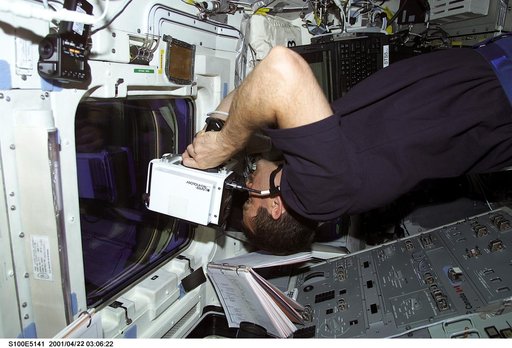MS Hadfield aims a laser range finder through a window on the aft flight deck of Endeavour