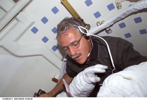 MS Phillips helps a fellow crewmember with his EMU before the first EVA of STS-100
