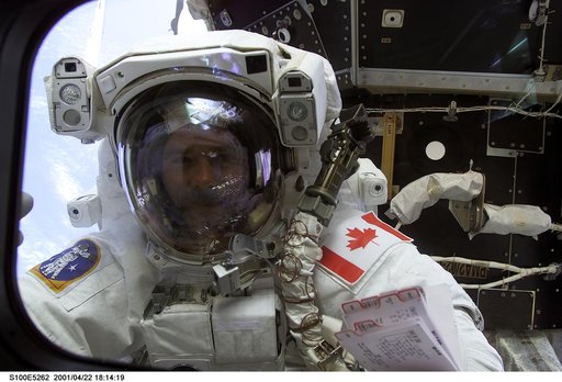 MS Hadfield waves through a flight deck window during the first EVA of STS-100