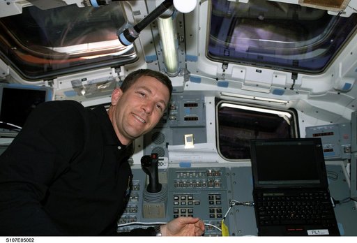 Husband smiles for the camera beside Columbia's AFD control panel during STS-107
