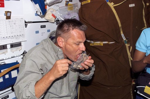 Sellers eats from a food container in the MDK during STS-121
