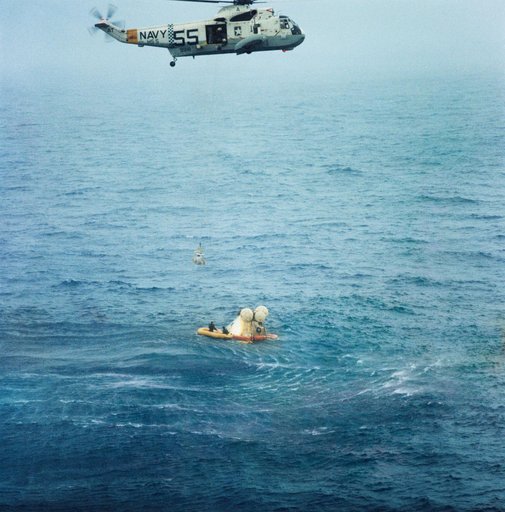 Member of Apollo 7 crew hoisted to helicopter during recovery operations