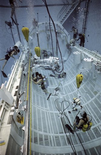 STS-37 crewmembers move CETA electrical cart along rail in JSC's WETF pool
