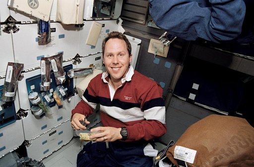 Astronaut Thomas Jones opens food package on middeck