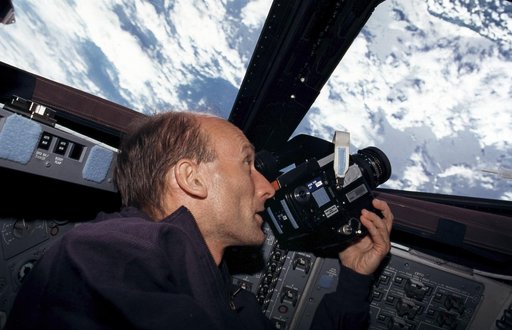 STS-99 MS Thiele aims a camera out of a window on OV-105's flight deck