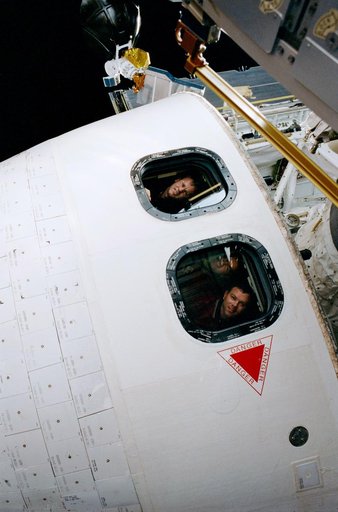 Astronauts in the windows of the orbiter as seen during EVA