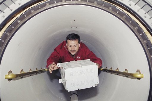 Pilot Altman carries a battery through the transfer tunnel during STS-106