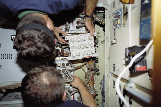 Morukov and Burbank work on the storage batteries in Zarya during STS-106