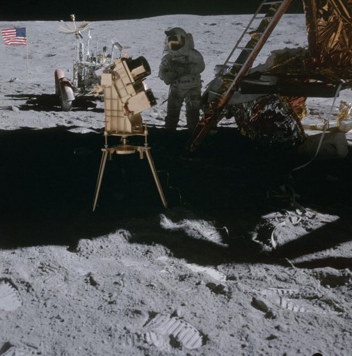 Astronaut John Young in shadow of Lunar Module behind ultraviolet camera